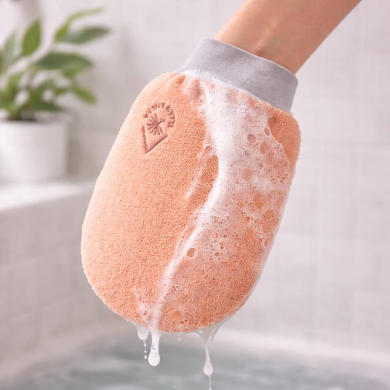 Gant de gommage corporel rose avec de la mousse.