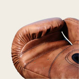 Gants de boxe en cuir brun avec coutures et rembourrage.